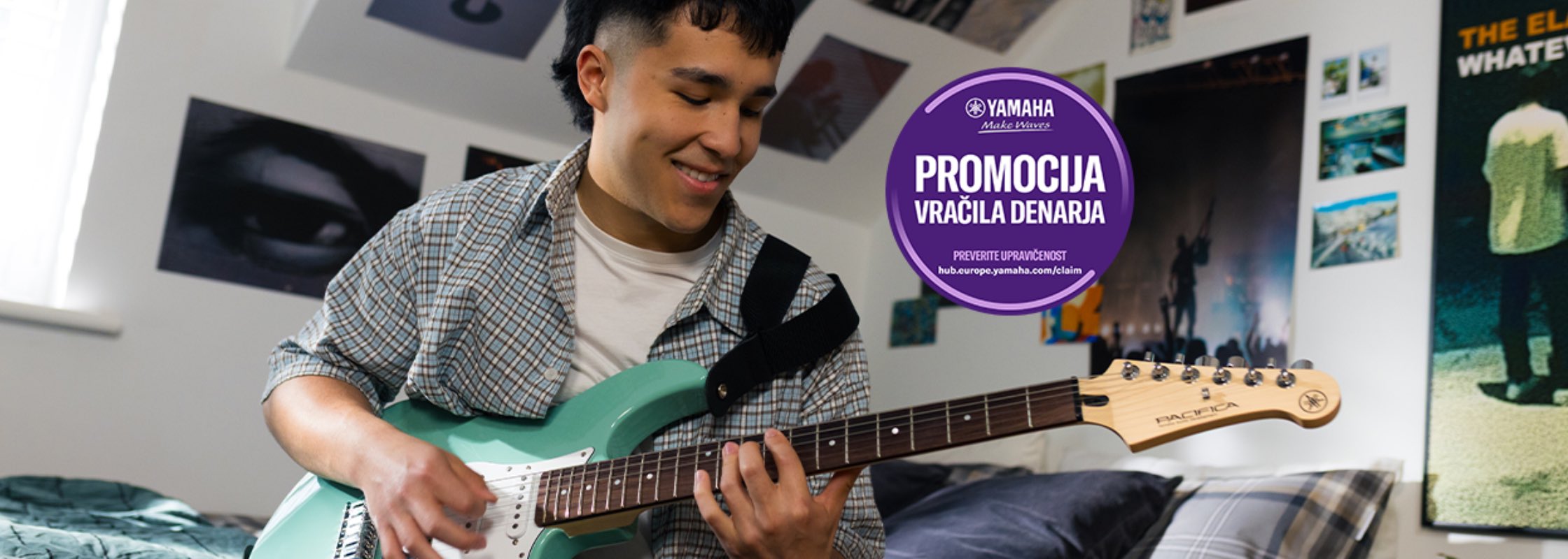 Young man playing a teal electric guitar in a bedroom, posters on the walls and a purple circular promo sticker reading 'PROMOCIJA VRACILA DENARA' nearby.
